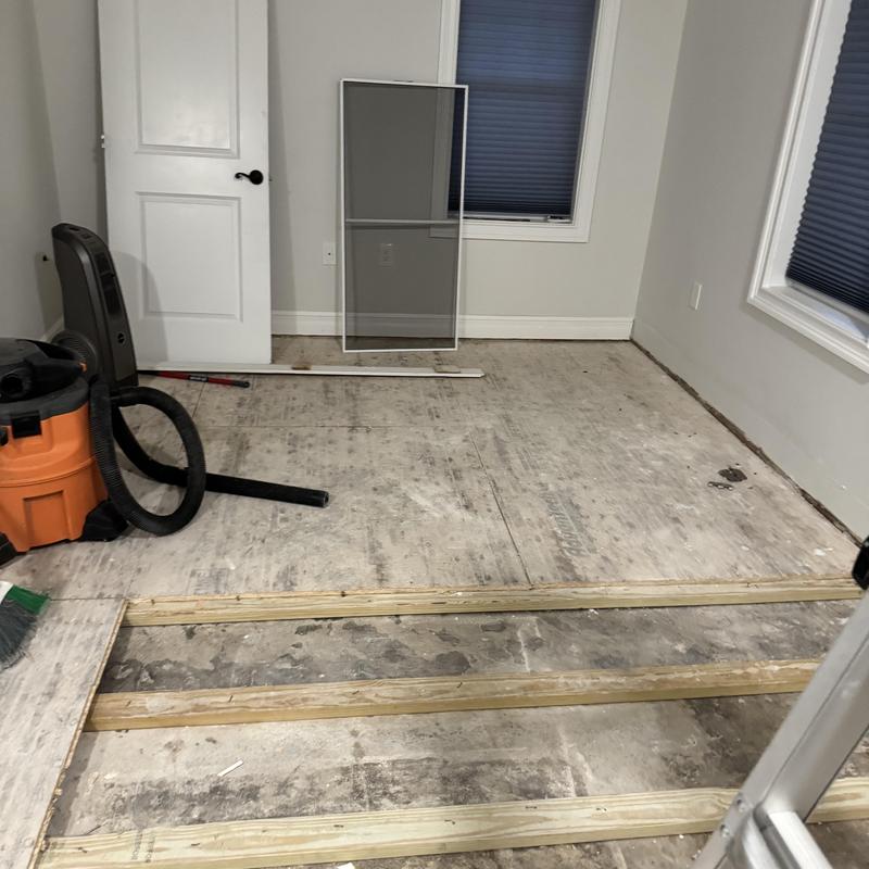 Subfloor framing with vacuum and tools in empty room