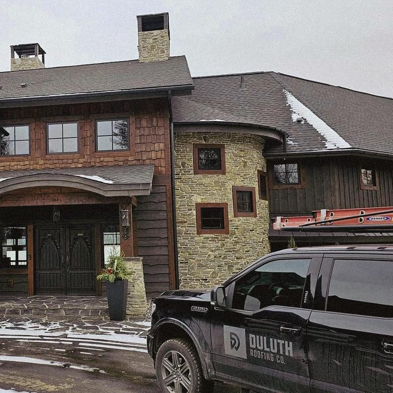 Roof shingles inspection on stone and wood exterior home Roof shingles inspection on stone and wood exterior home