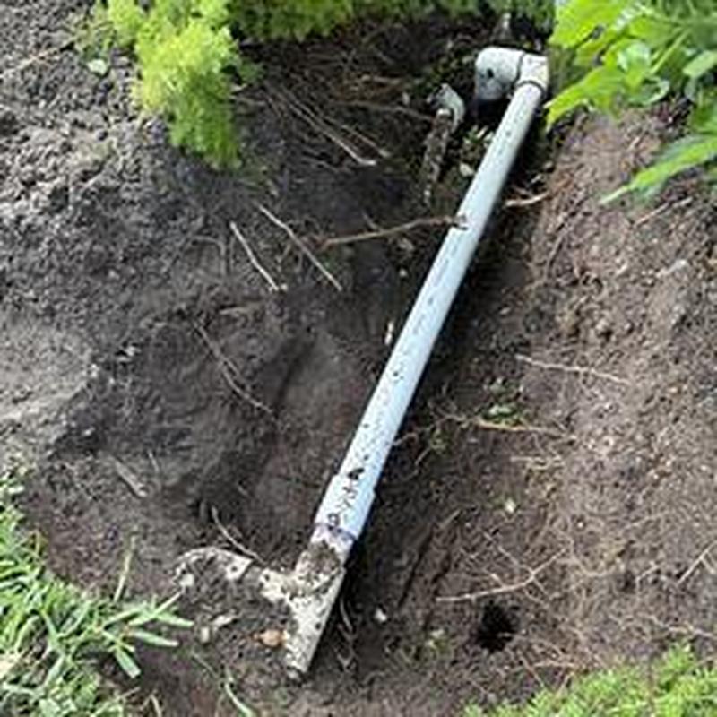Backflow assembly piping exposed in dug trench outdoors