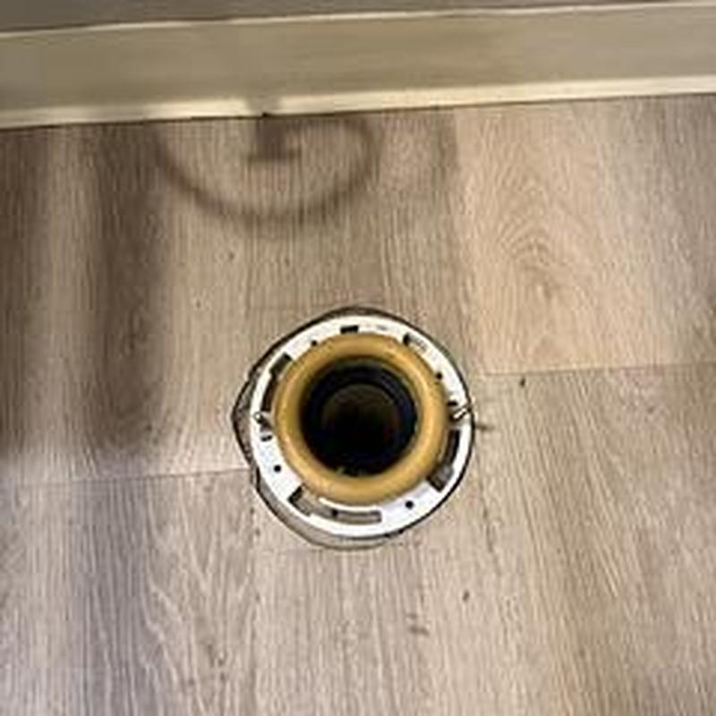 Toilet flange installed on bathroom floor near baseboard