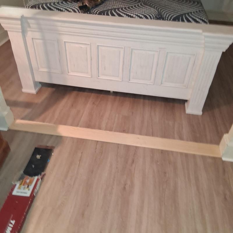 Wood transition strip between vinyl floors installation