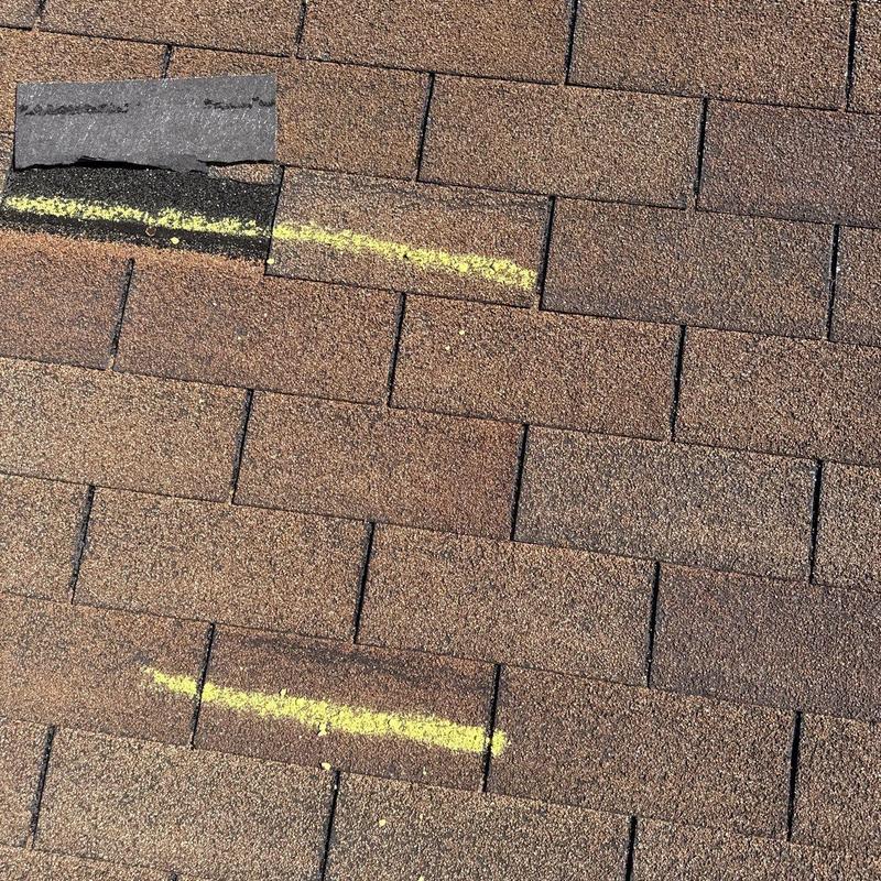 Roof shingles with hail damage marked in yellow chalk