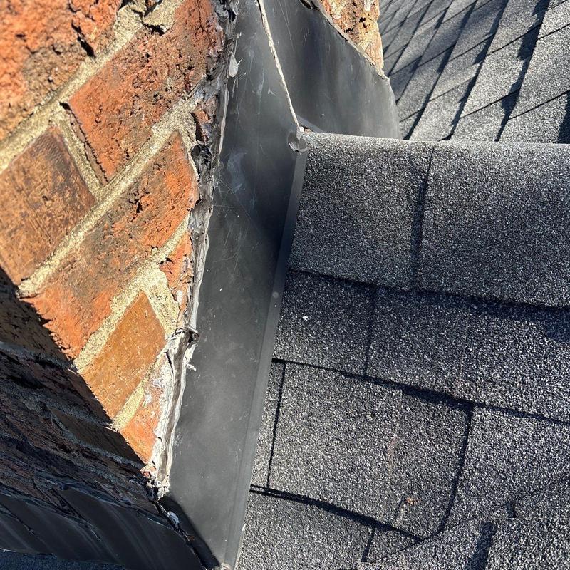 Roof flashing and shingle inspection on brick chimney