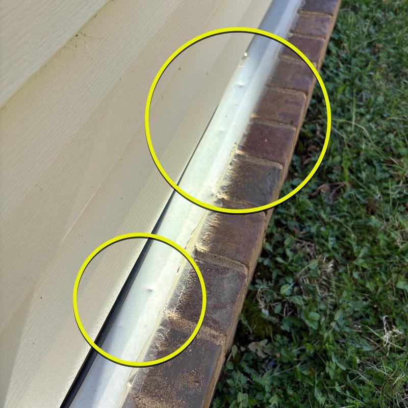 Metal flashing with hail damage dents near brick base