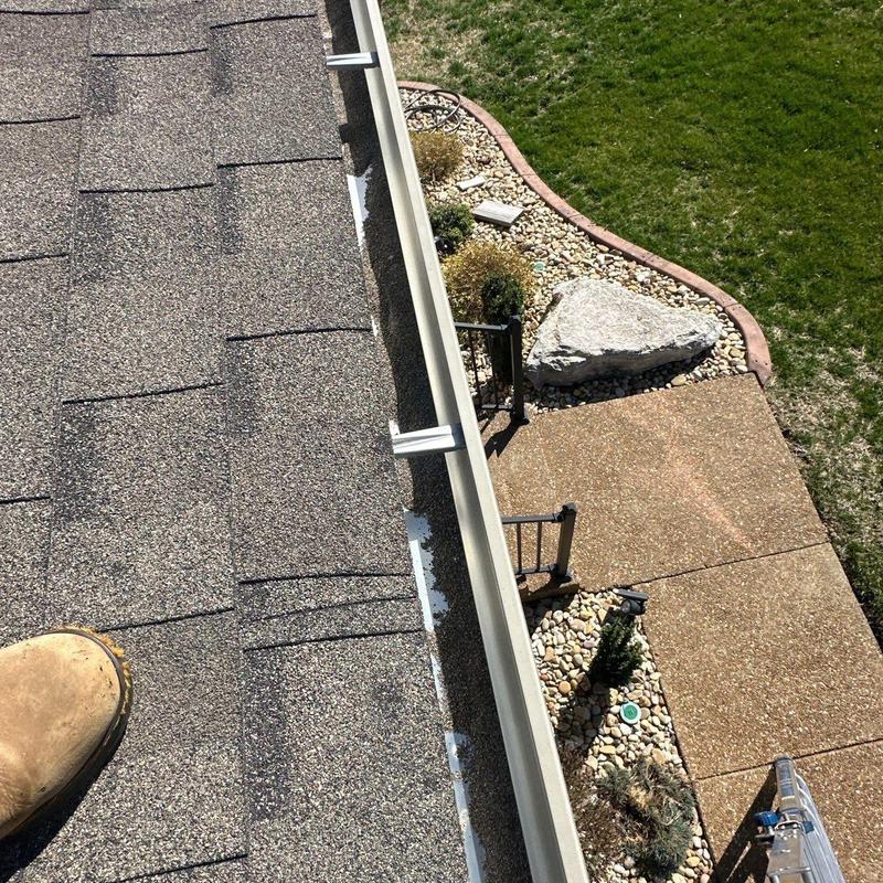 Roof shingles and gutter with sporadic debris buildup