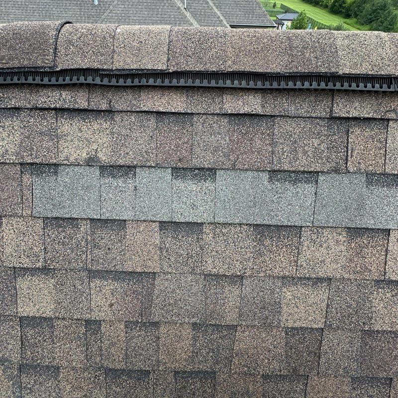 Asphalt roof shingles with hail damage near ridge vent