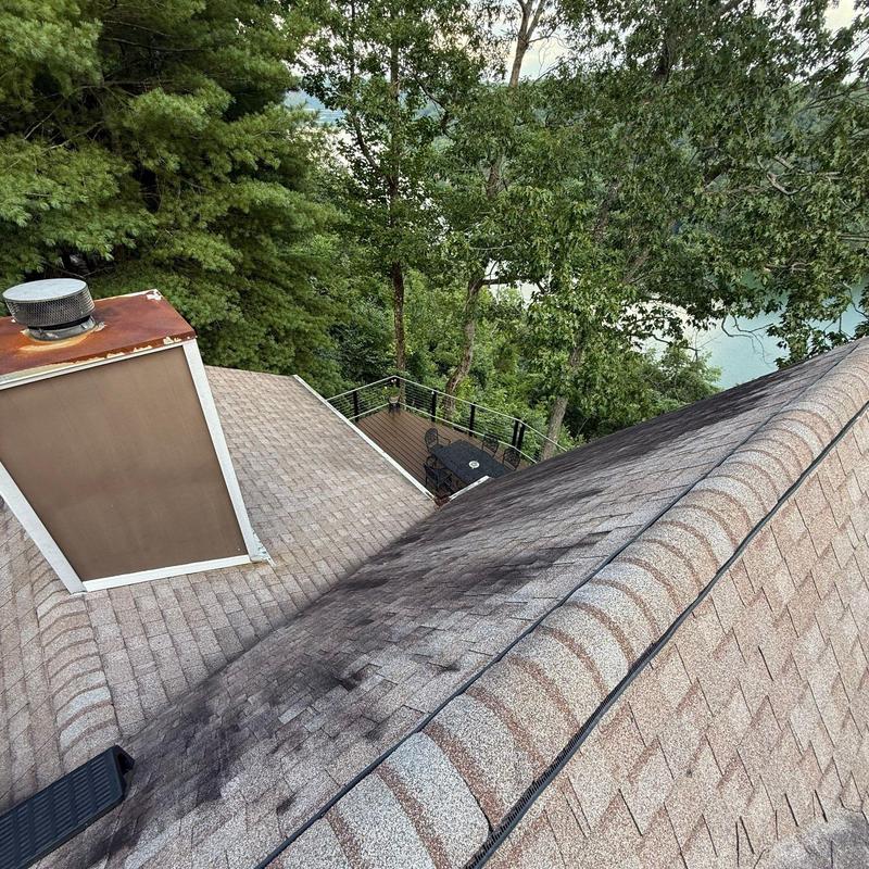Asphalt shingle roof with dark streaks near chimney