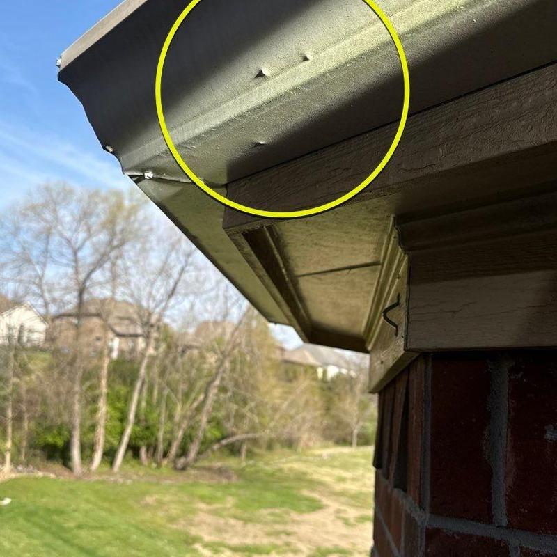 Metal gutter with hail damage dents circled in yellow