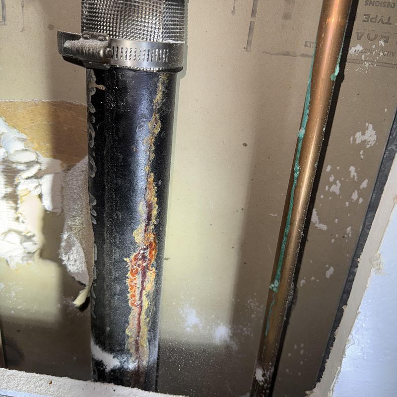 2-inch cast iron drain pipe with rust damage between floors