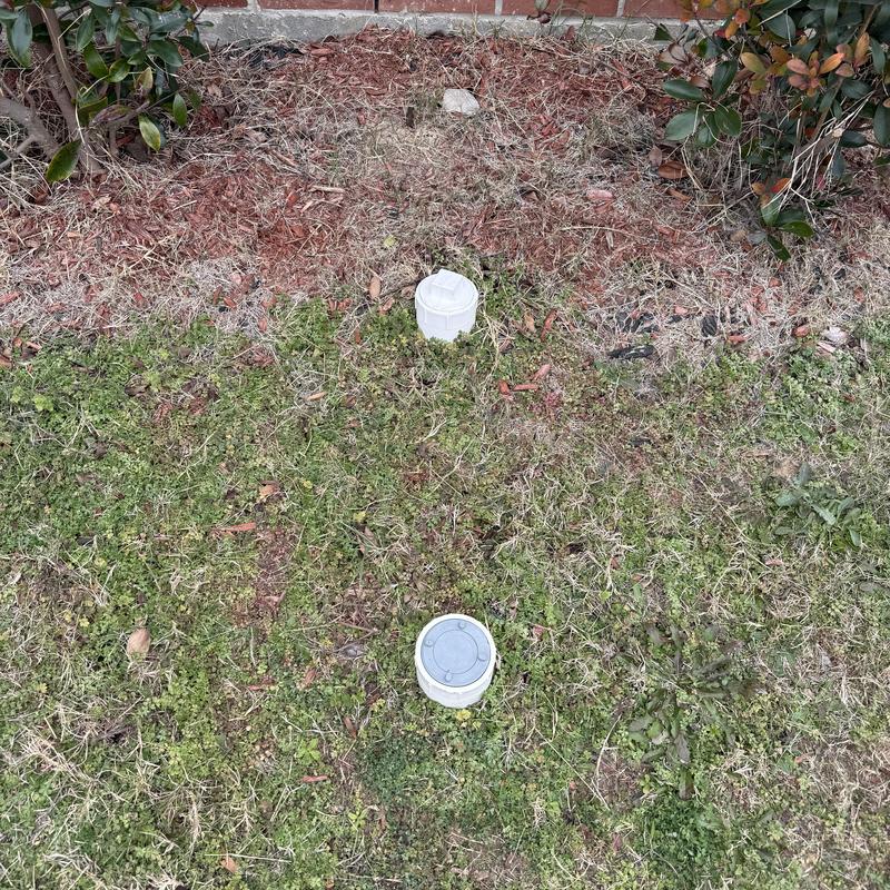 Drain cleanout caps installed in yard near building