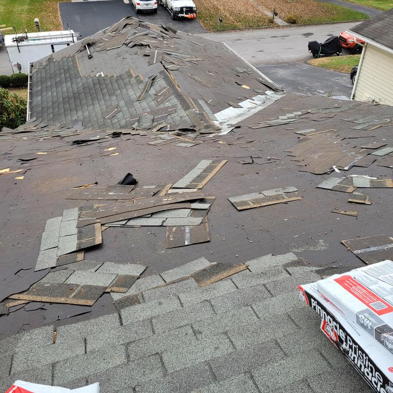 Asphalt shingle roof with damaged and removed shingles