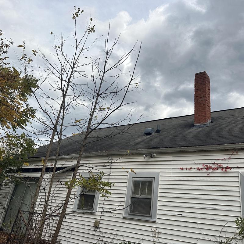 Asphalt shingle roof on aging house with chimney