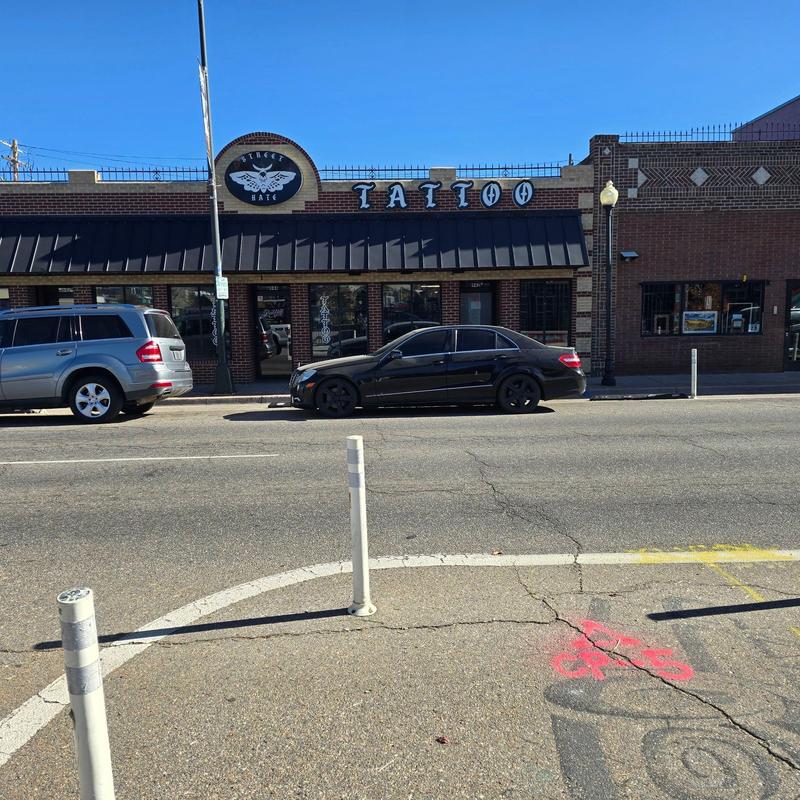 Tattoo shop exterior with parked cars and street view Tattoo shop exterior with parked cars and street view