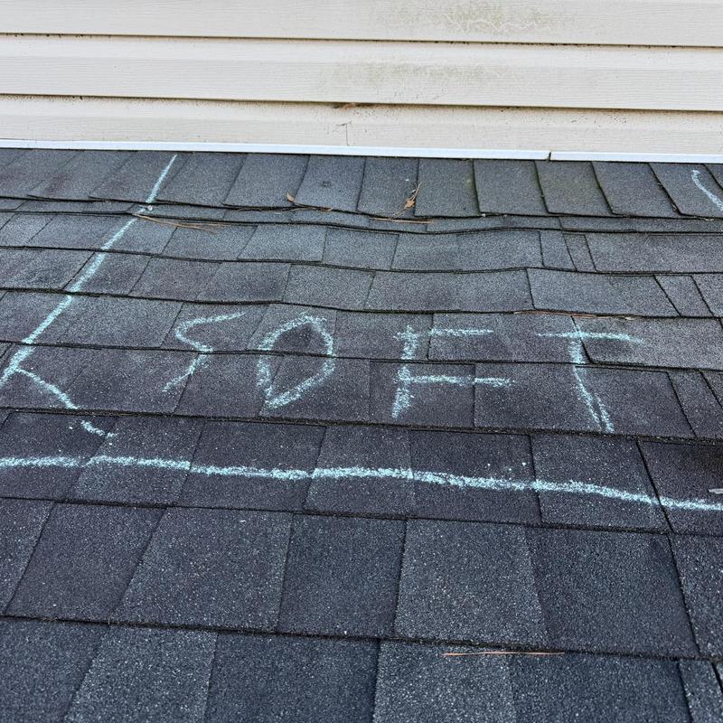 Roof shingles with chalk markings indicating damage area