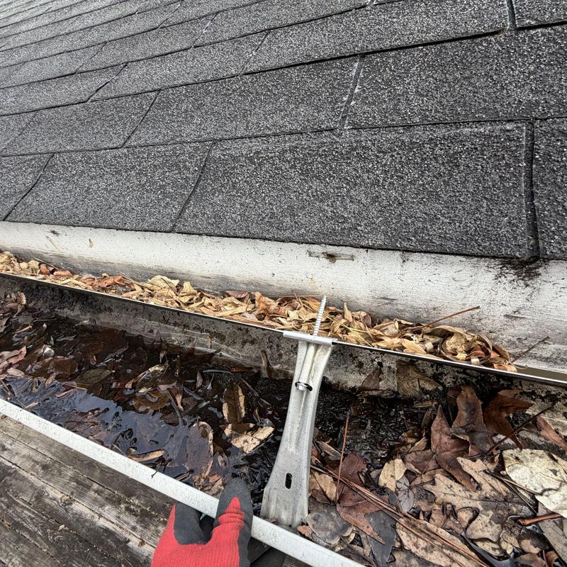 Gutter section detached with debris buildup on roof edge