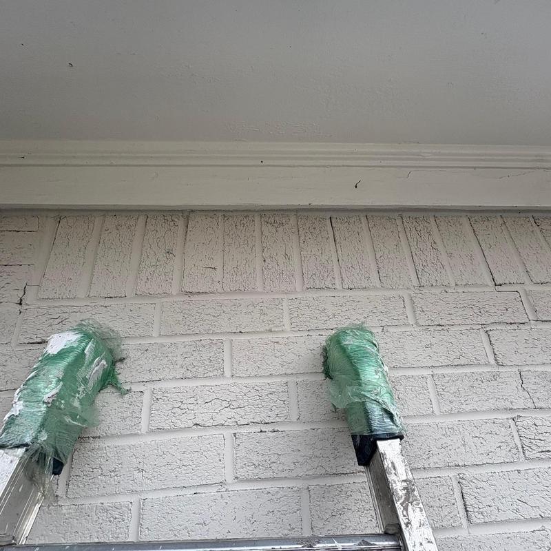 Extension ladder with padded legs against brick wall