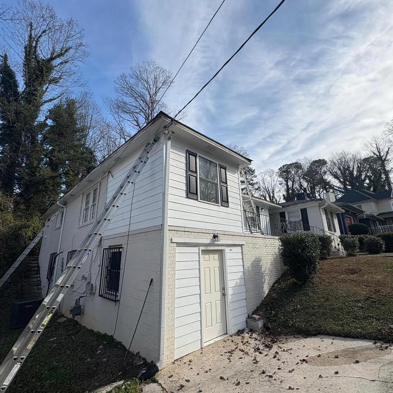 Seamless gutters installation on white house exterior