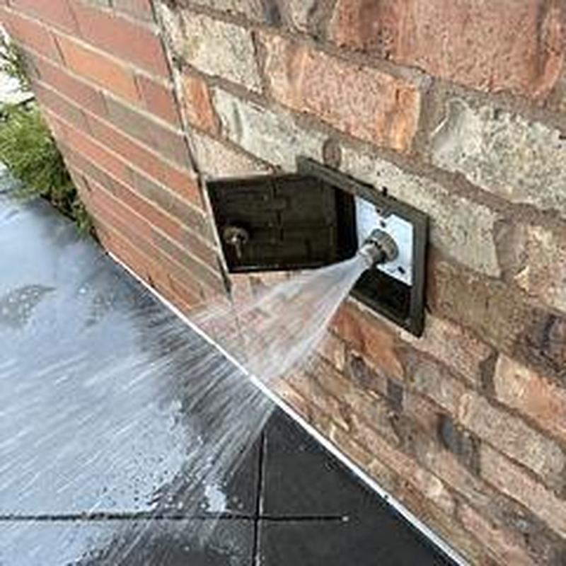 Outside hose bib with water flow on brick wall