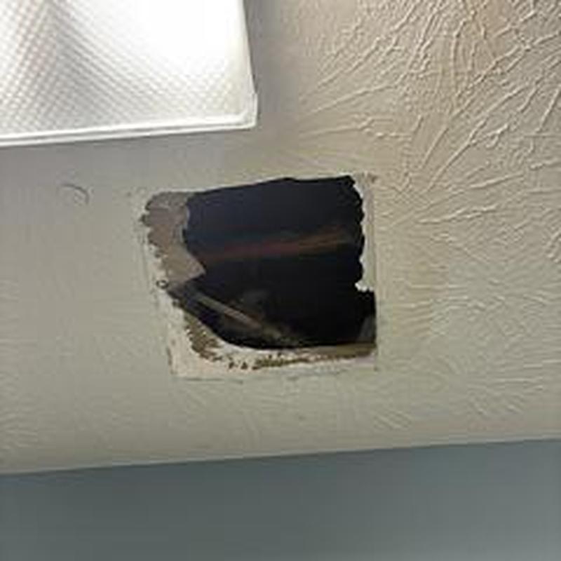 Ceiling drywall hole showing water damage and leak inspection