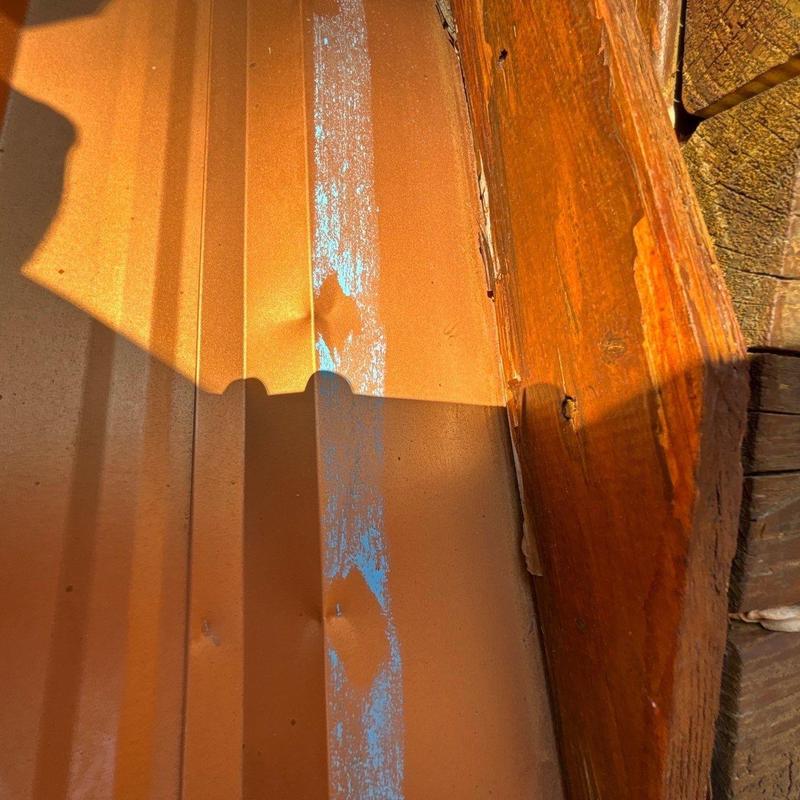 Metal roof panel with dent and sealant residue