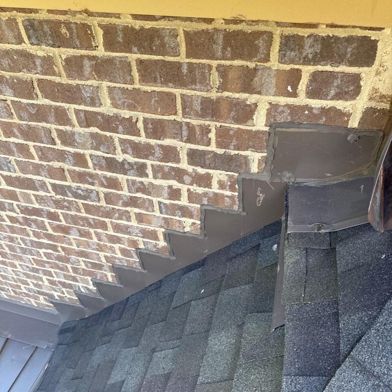 Roof flashing along brick wall and shingle roof junction