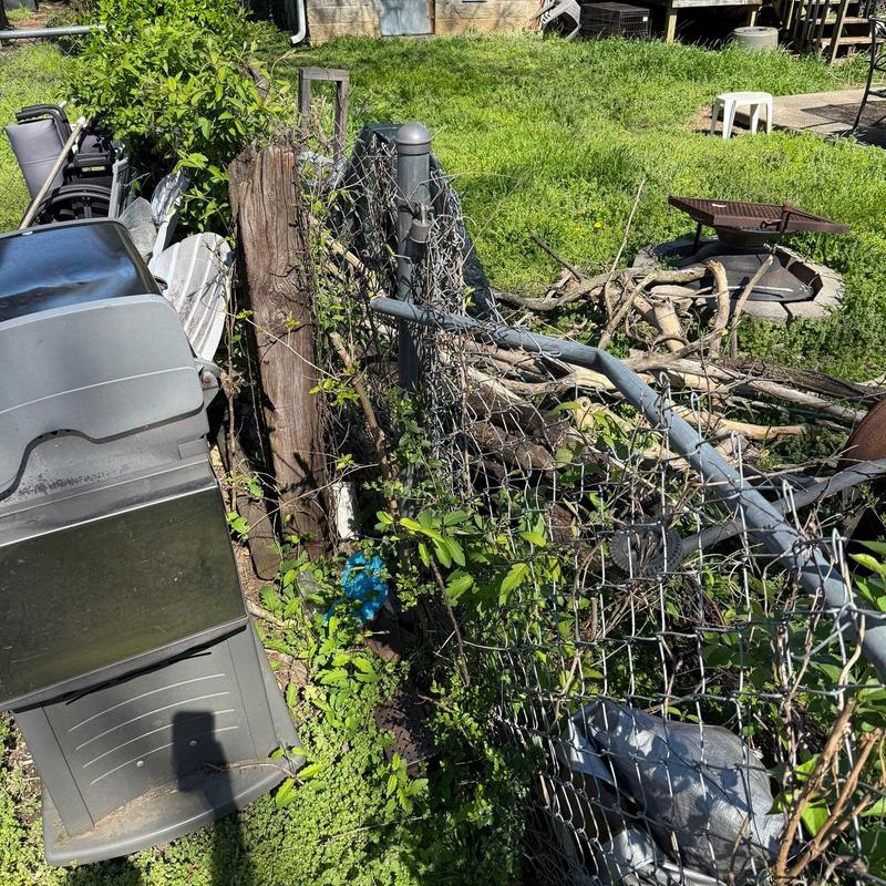 Chain link fence bent and overgrown with plants outdoors
