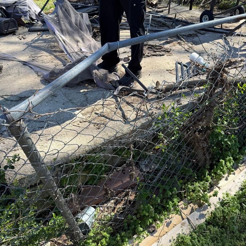 Chain link fence bent and damaged with uprooted post