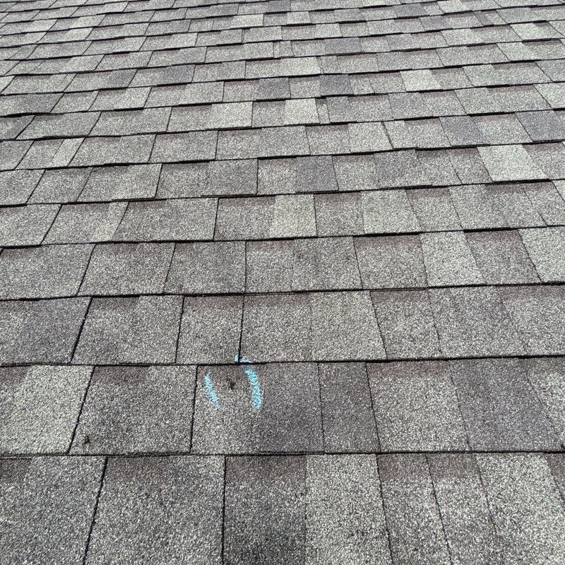 Asphalt roof shingles with hail damage marked for repair