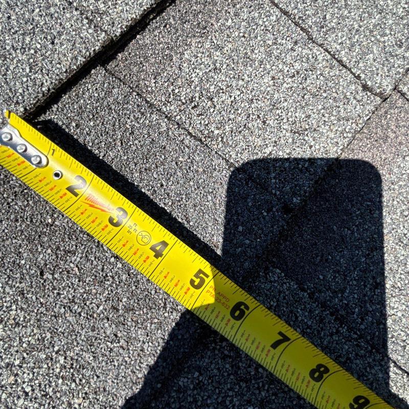 Asphalt shingles showing hail damage with measurement tape