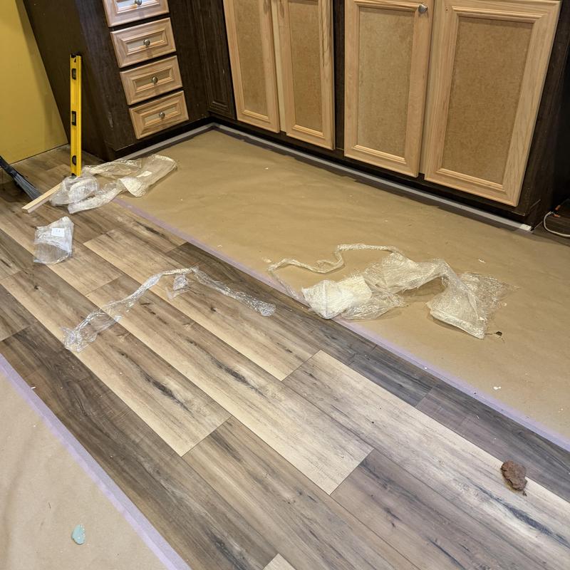 Wood laminate flooring installation near kitchen cabinets
