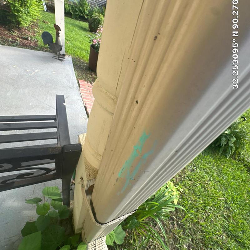 Rain gutter with detached downspout section near porch