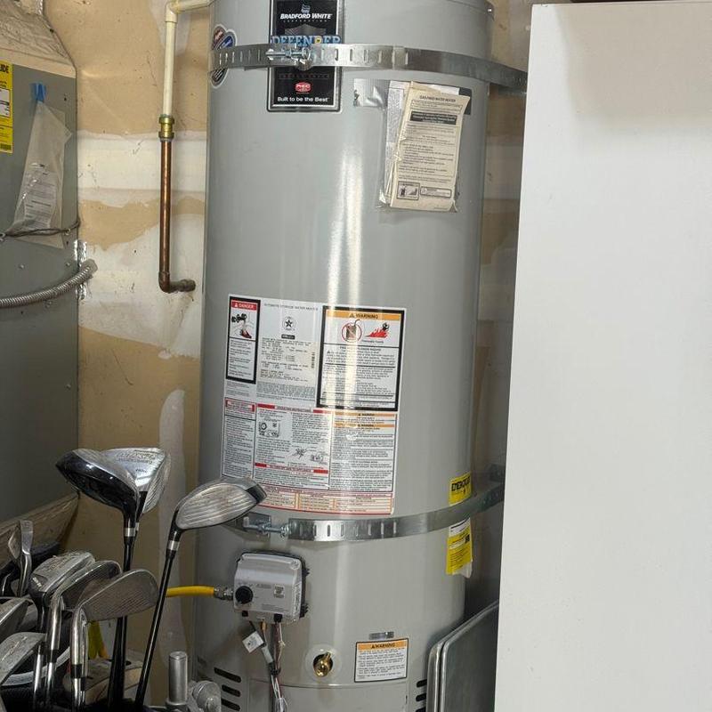 Water heater with flushing setup and golf clubs nearby