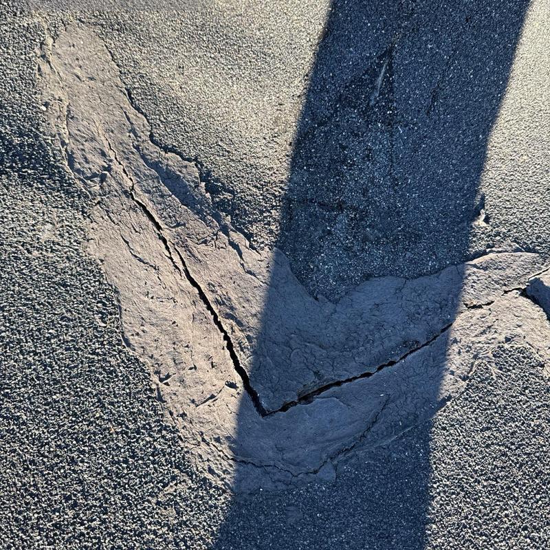 Asphalt roof crack with damaged sealant and shadow