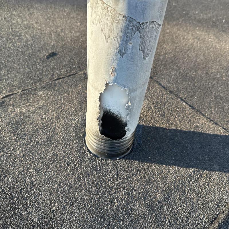 Roof vent pipe with large corrosion hole on shingle roof