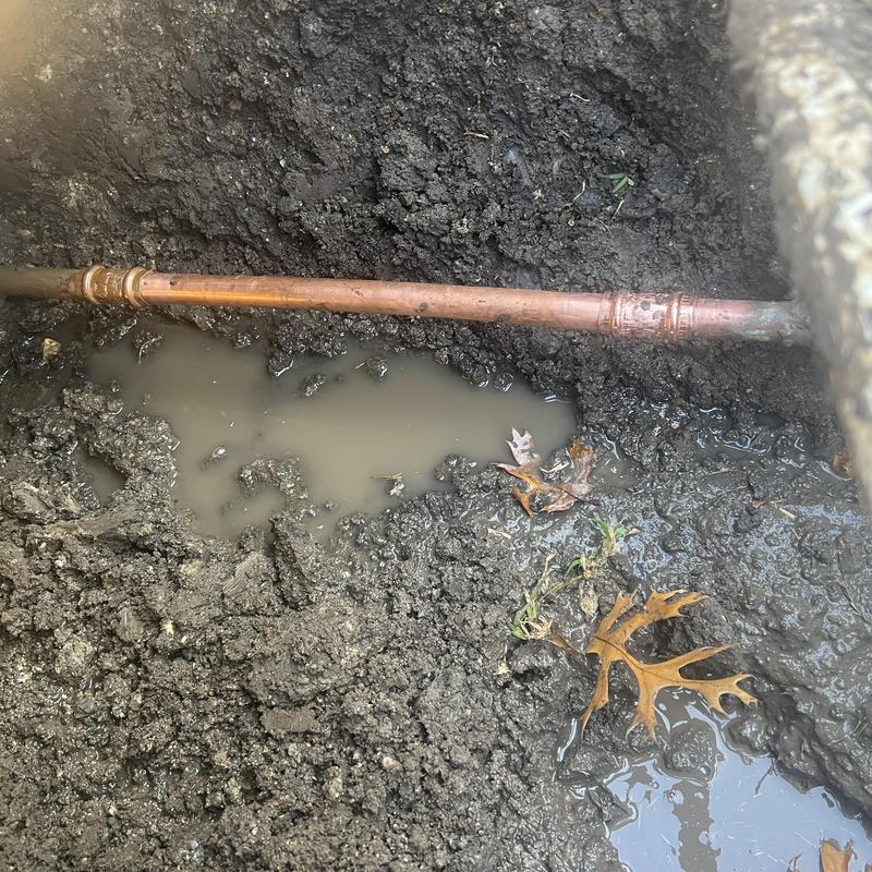 Copper water main pipe with soil and water pooling