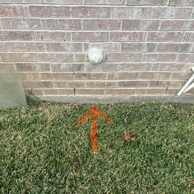 Sewer cleanout with orange arrow marking in grass