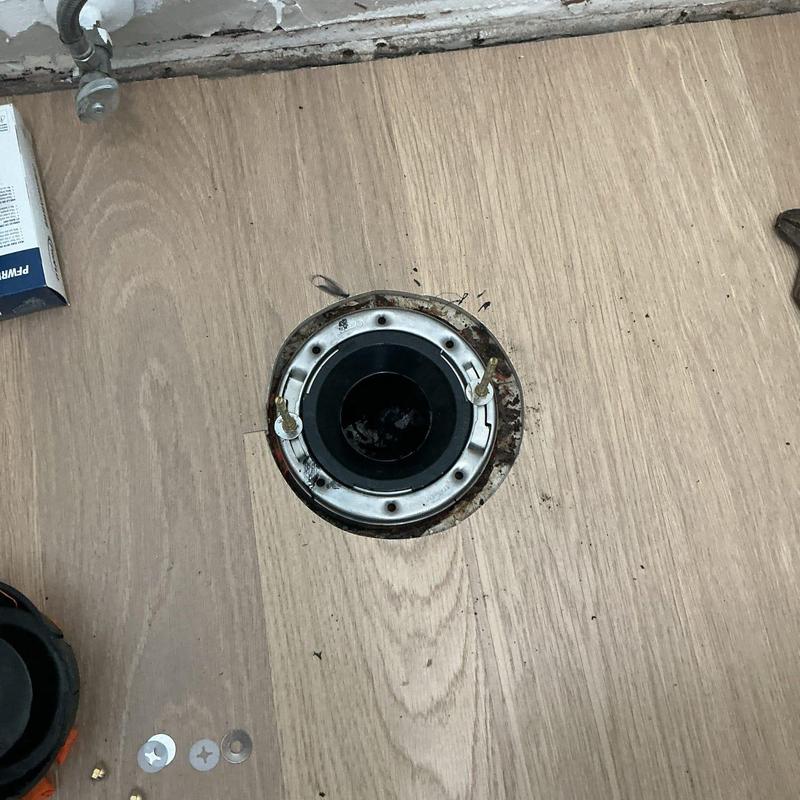 Toilet flange with new glue-in hardware on wood floor