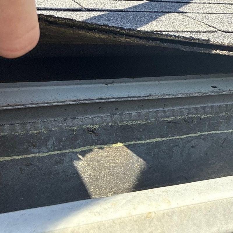 Roof flashing inspection with shingle damage visible