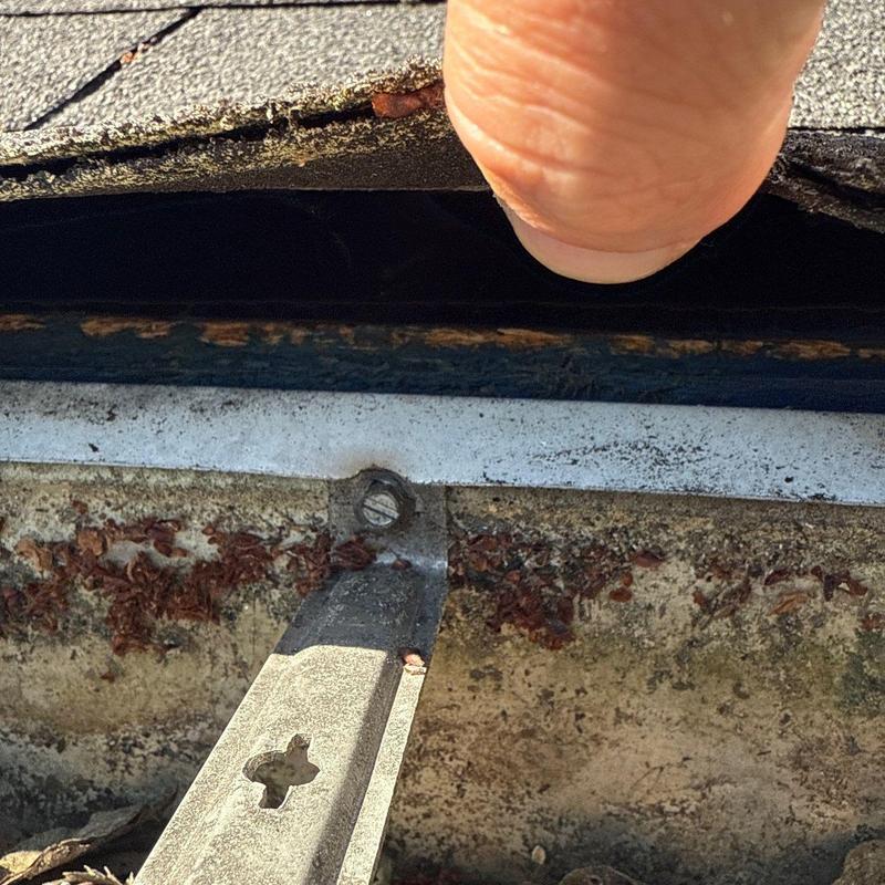 Asphalt shingle edge lifting above rusted metal drip edge