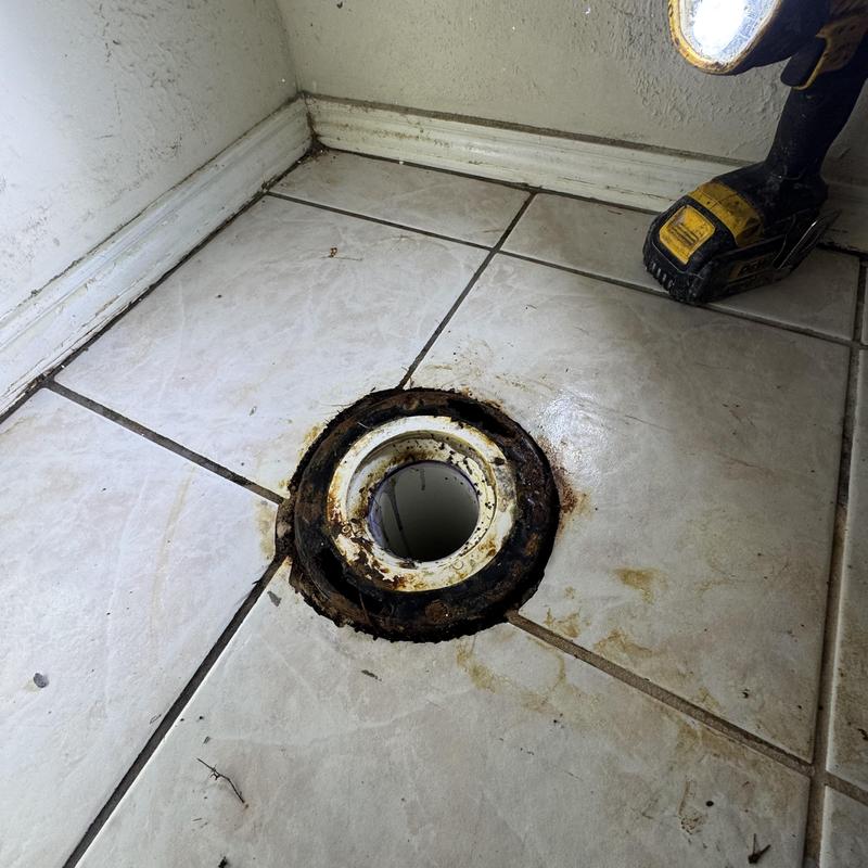 Toilet flange on tiled floor with power drill nearby