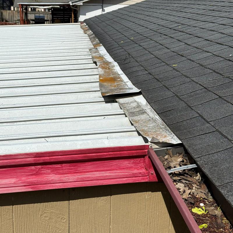 Metal roof edge and shingle roof junction with rust damage