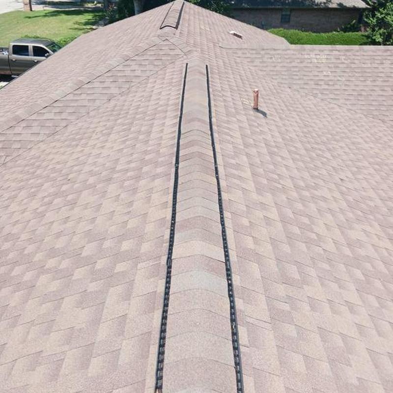 Asphalt shingle roof with ridge vent under clear sky