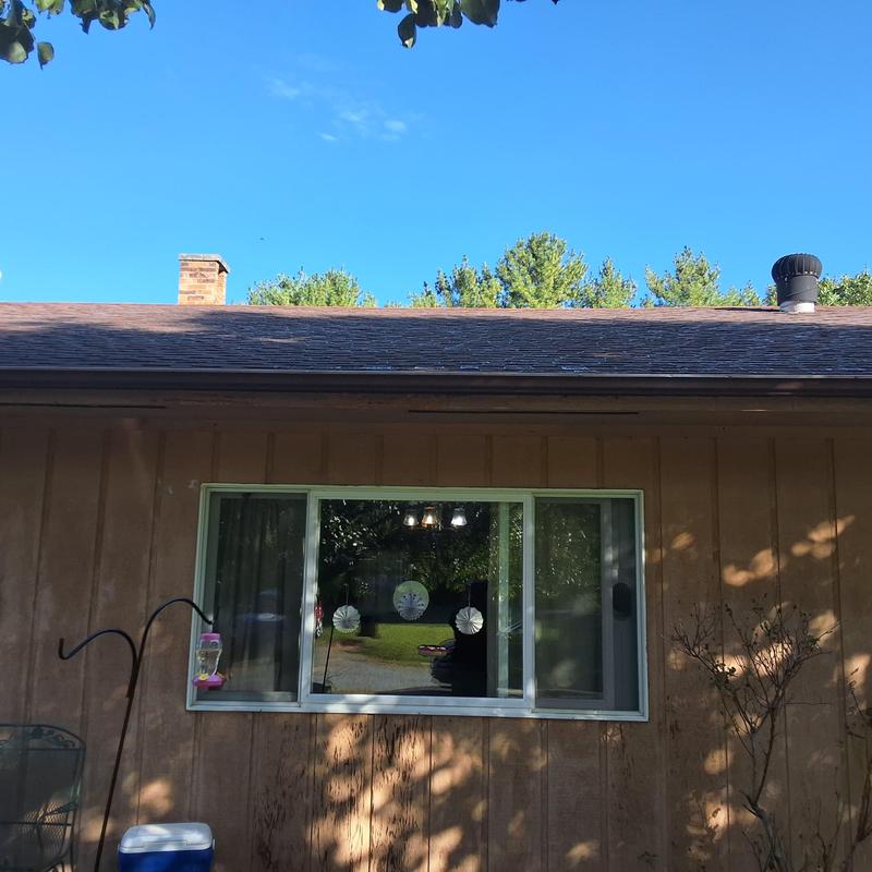 Roof shingles on brown home exterior under clear sky