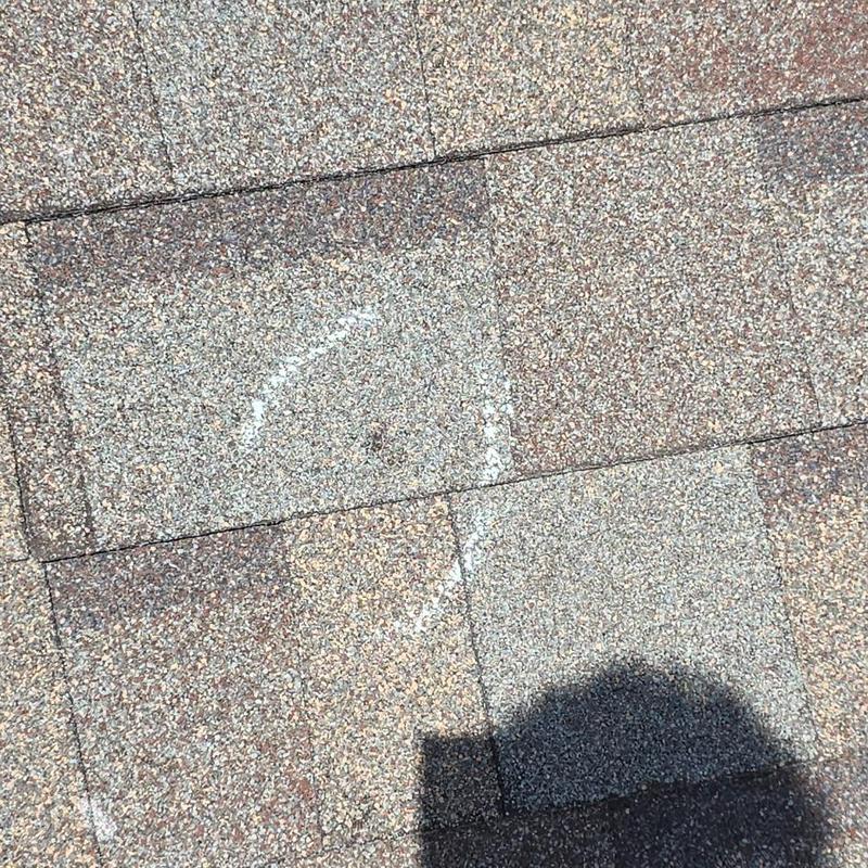 Roof shingles with hail damage marked for repair
