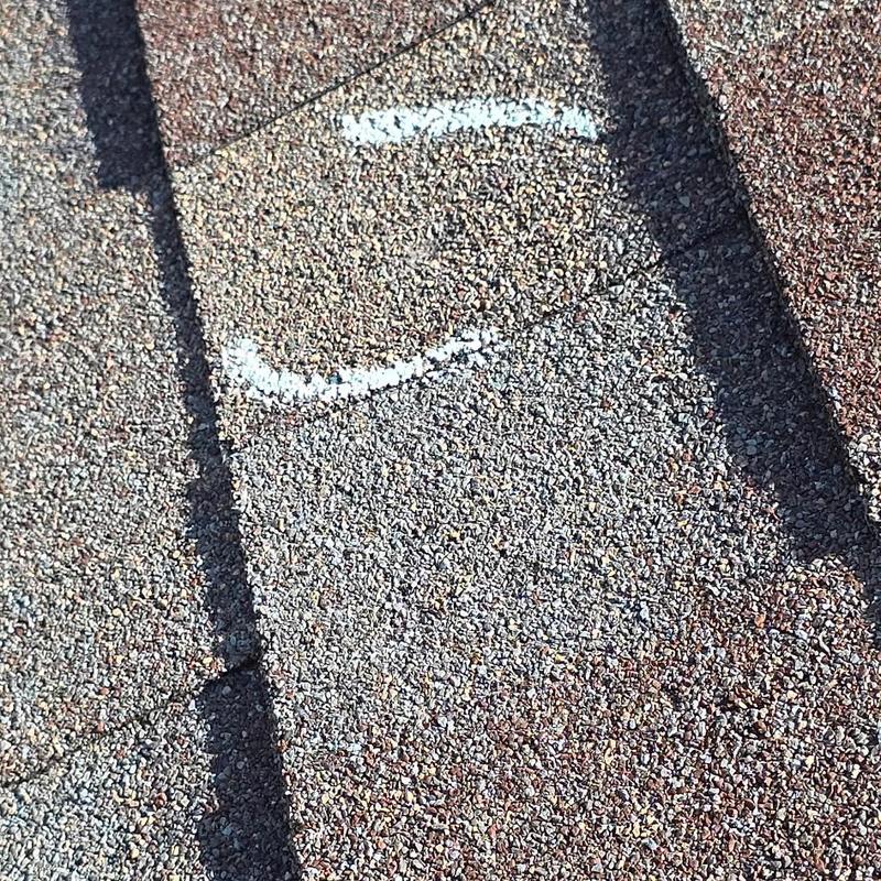 Asphalt roof shingle with hail damage marked for repair