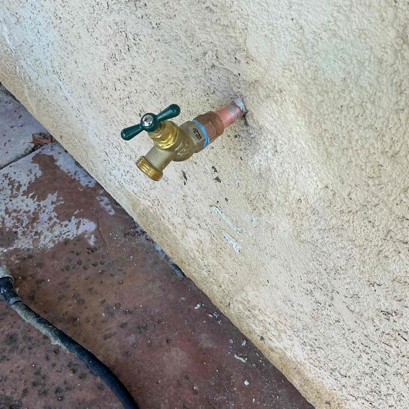 Outdoor water sillcock valve attached to stucco wall