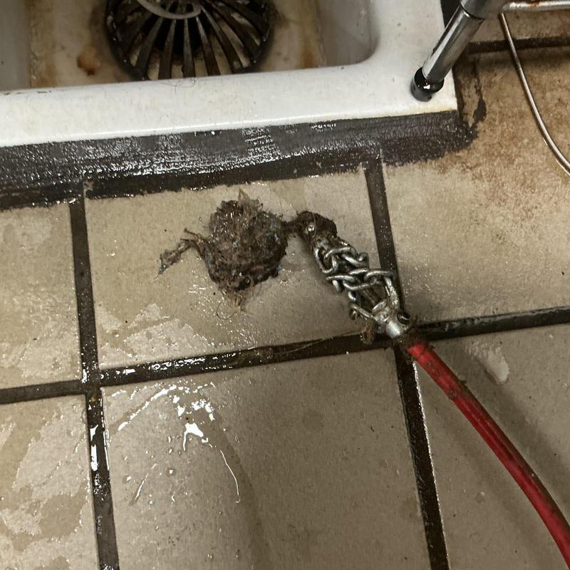 Drain snake with debris and mop hair removal near sink drain