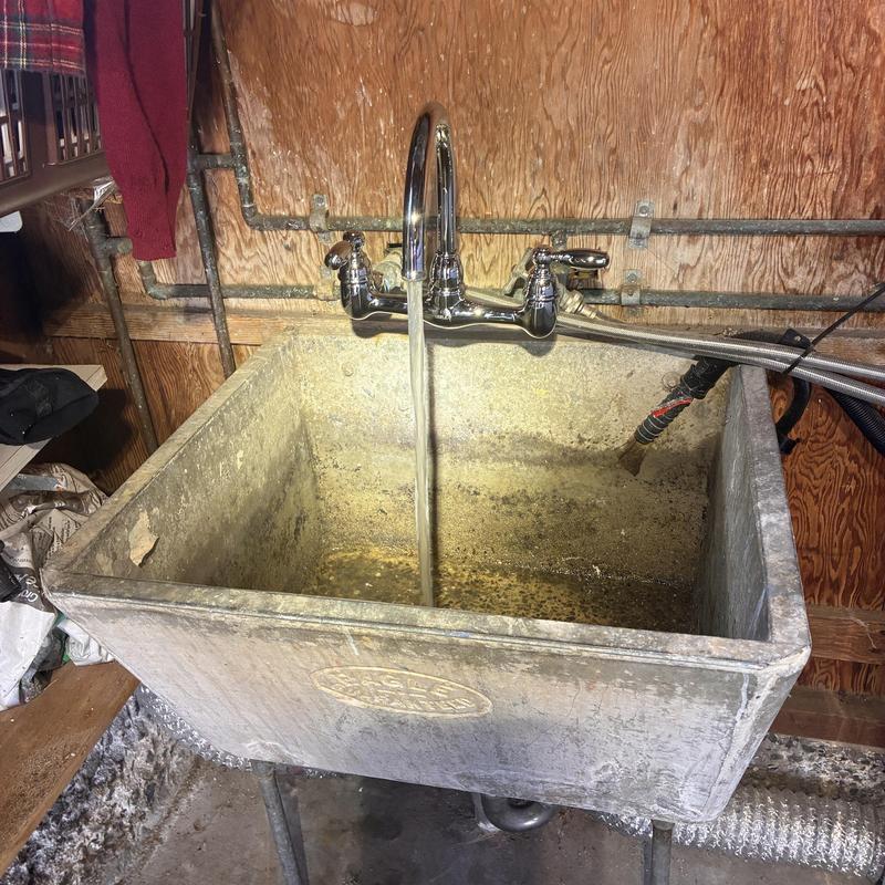 Laundry faucet with water flow over concrete basin