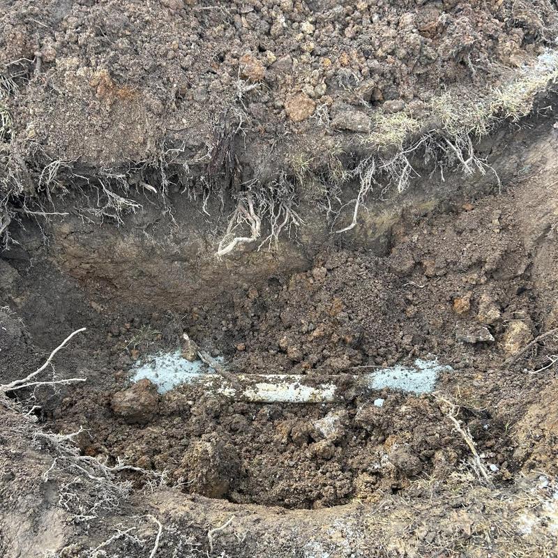 Sewer line with crack and debris in soil excavation