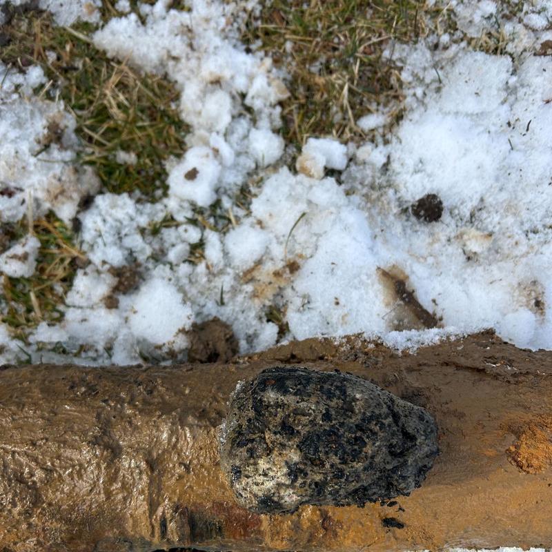 Sewer line with large crack and lodged rock obstruction